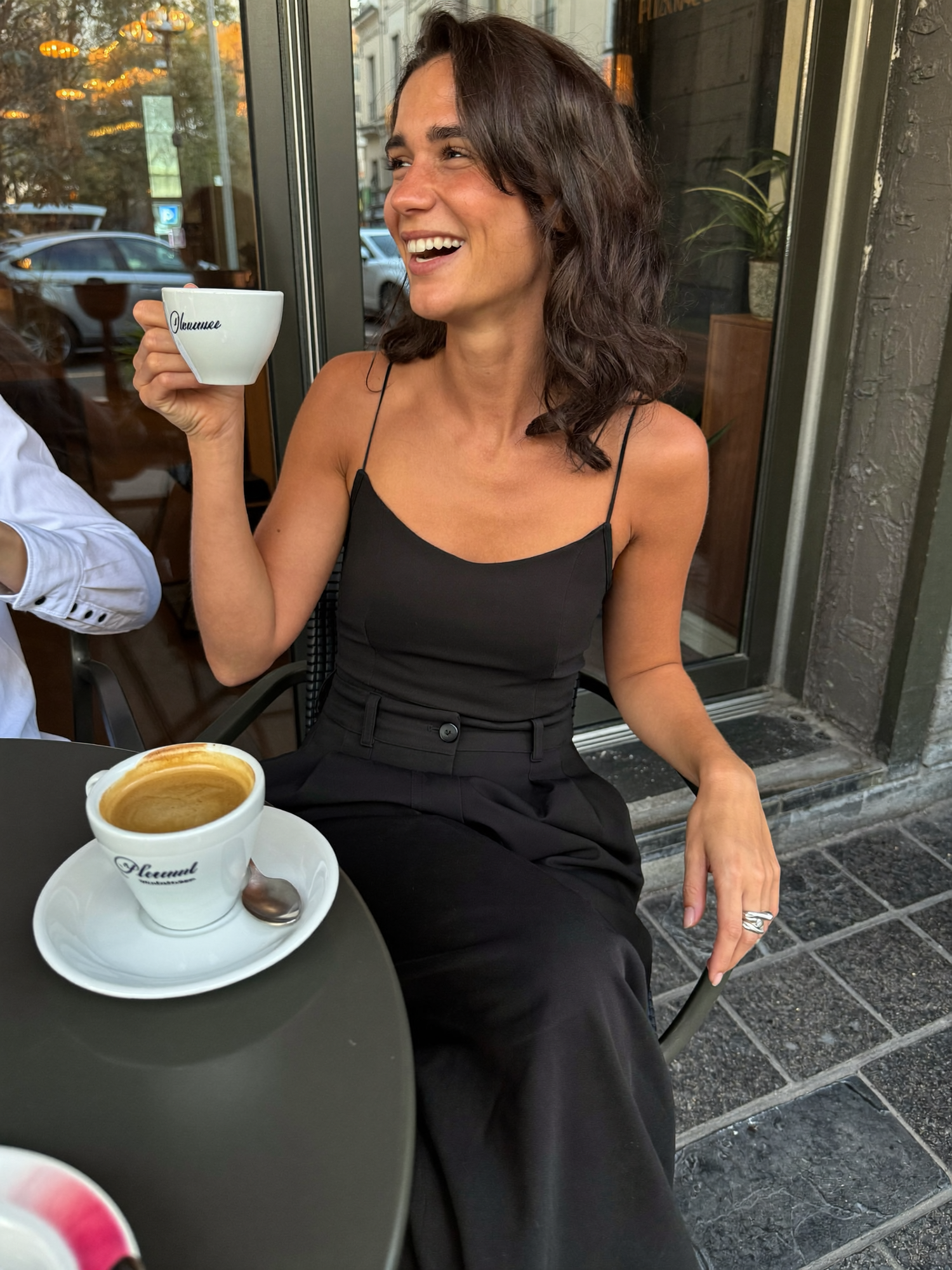 Cliente Bianca Romano — jumpsuit nero, caffè all'aperto